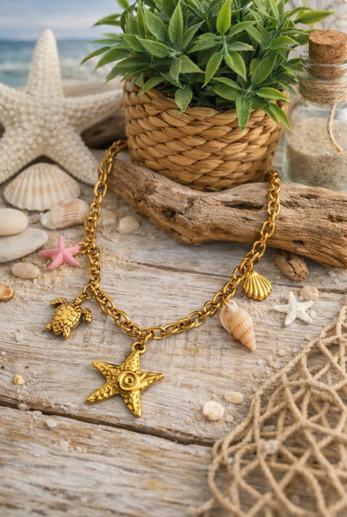 Collier Procida en acier inoxydable doré avec charms marins, étoile de mer, tortue, coquillages et détail rose sur décor plage.