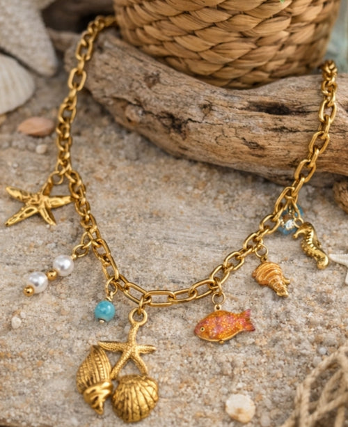 Collier Positano acier inoxydable doré femme avec charms marins, coquillages, étoile de mer, poisson, hippocampe, perles et détails turquoise.