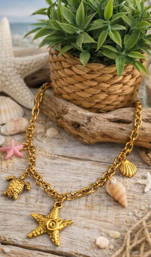 Collier Procida en acier inoxydable doré avec charms marins, étoile de mer, tortue, coquillages et détail rose sur décor plage.