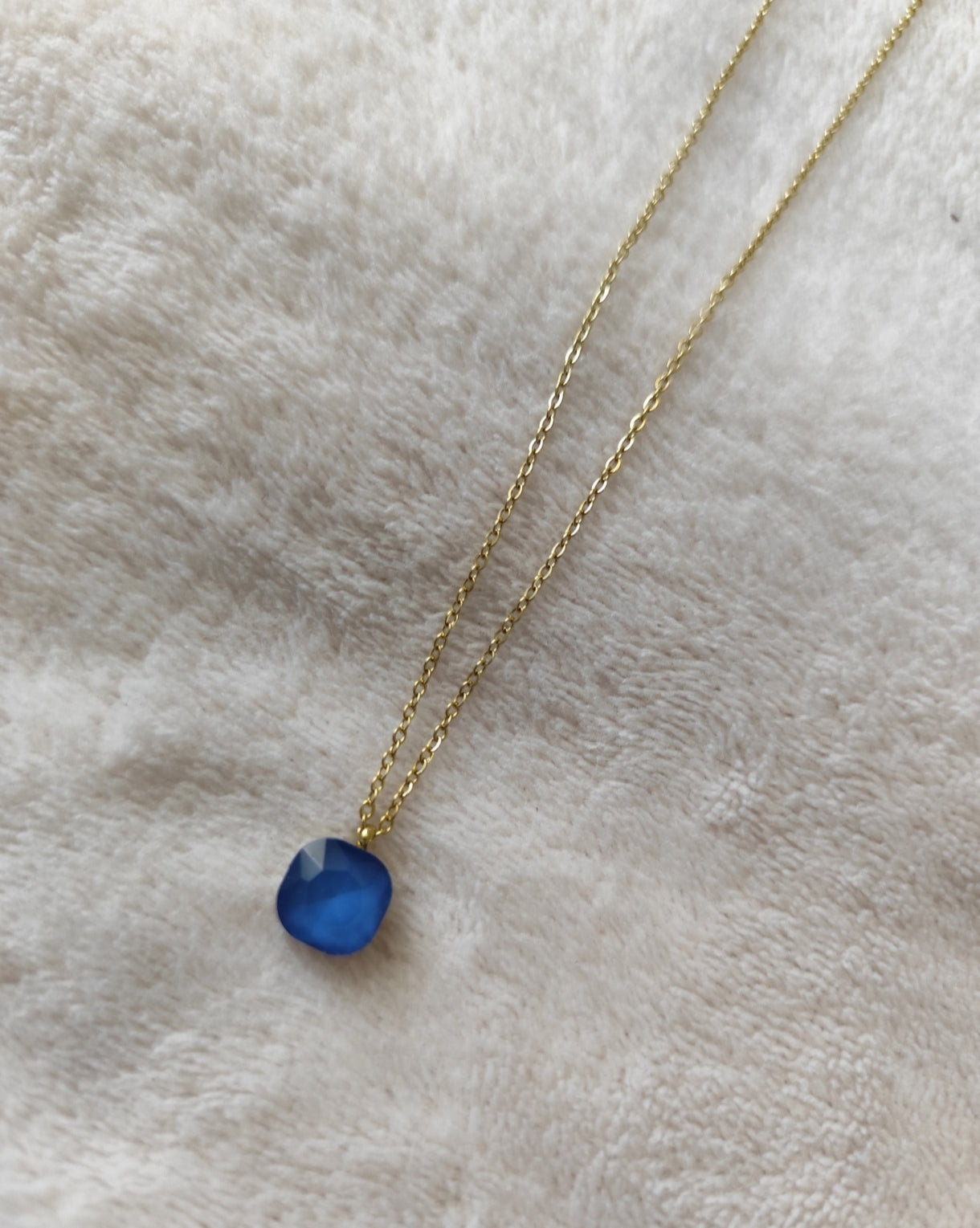 Collier Nerja en acier inoxydable doré avec pendentif en pierre facettée colorée bleu disponible en plusieurs coloris.