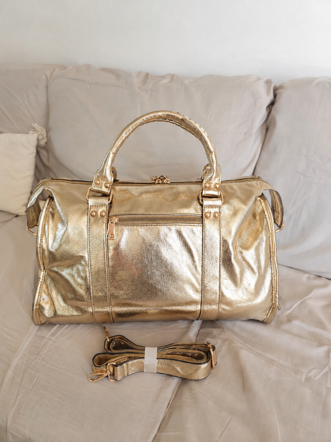 Sac de cours ou de voyage en cuir métallisé doré, style duffle bag, avec bandoulière amovible et finitions dorées, design élégant et spacieux